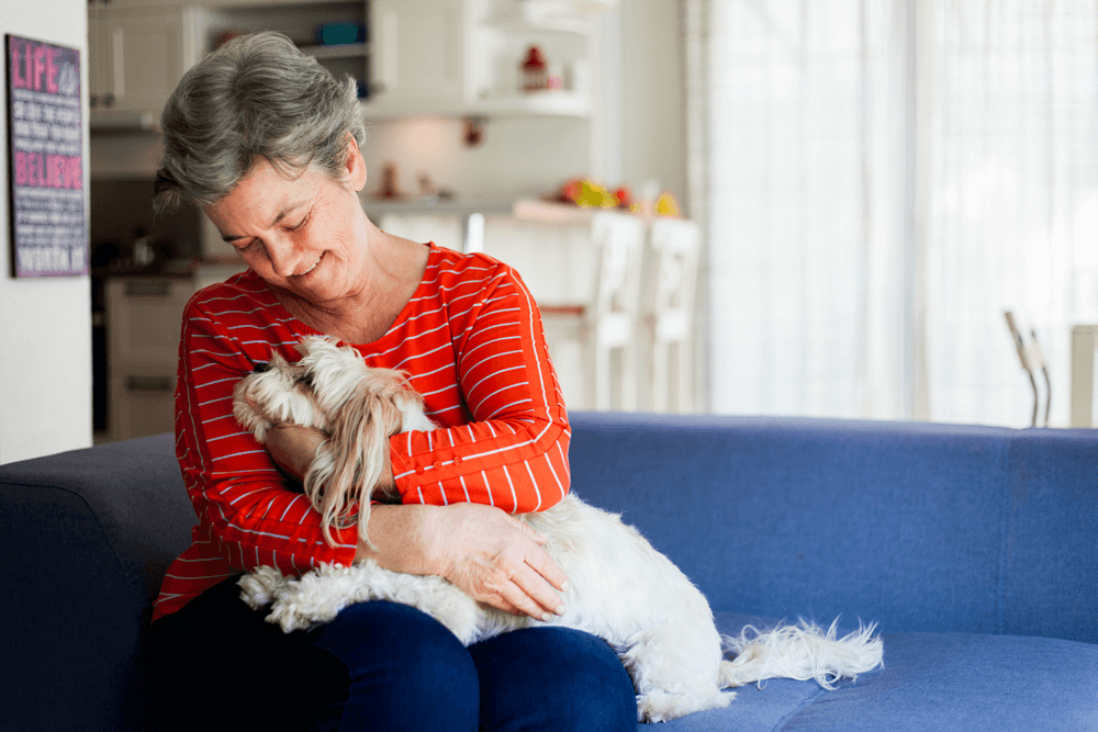 A woman on a couch holding her dog