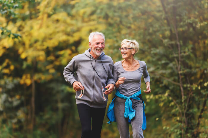 Senior couple smiling and jogging through park